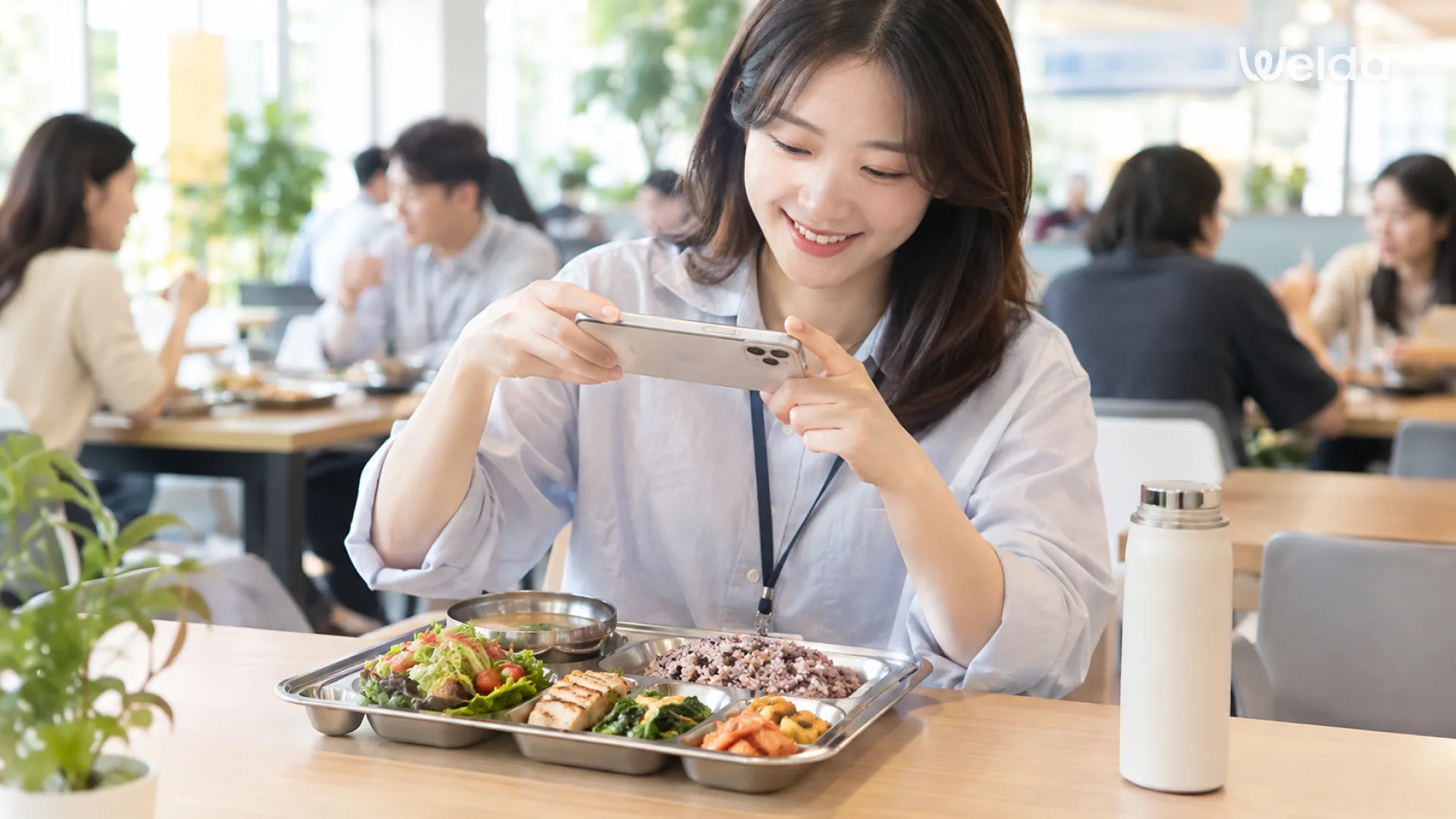 구내식당에서 식판 위 식사를 스마트폰으로 촬영해 기록하는 임직원 — 웰다 앱으로 식사와 혈당 반응을 확인하는 모습